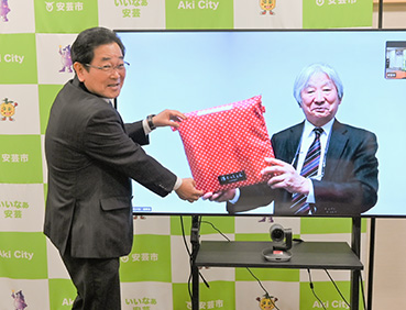 高知県安芸市との浮くっしょん贈呈式の写真。会長辰野はオンラインで出席し、大型モニターに映っています。