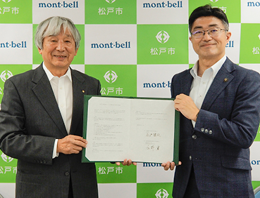 松戸市と株式会社モンベルの包括連携協定締結式の様子。左からモンベル代表・辰野勇、松戸市・松戸隆政 市長が包括協定書を掲げています。