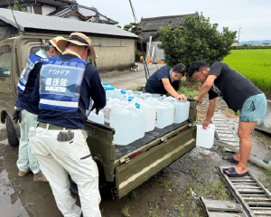 軽トラックからポリタンクに入った水を降ろす様子。