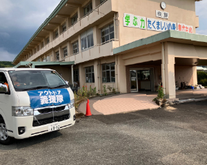 小学校の玄関前に支援物資を載せた車が停まっています。