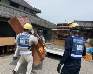 複数のアウトドア義援隊のメンバーが壊れた家具を運び出しています。
